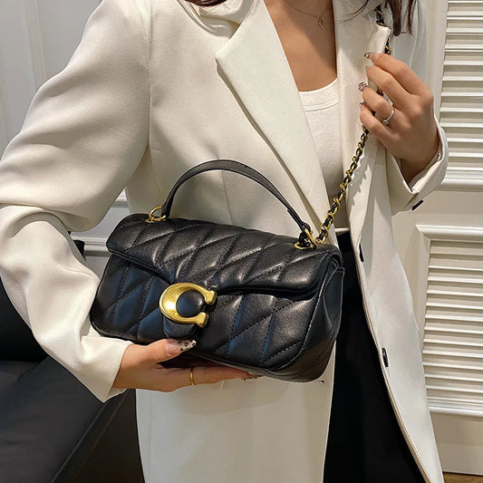 Woman holding EtherealBe black quilted leather luxury square chain handbag with gold hardware and top handle