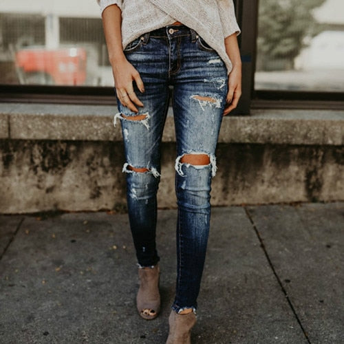 Woman wearing dark wash boyfriend ripped jeans for women with knee rips and frayed hem paired with ankle booties