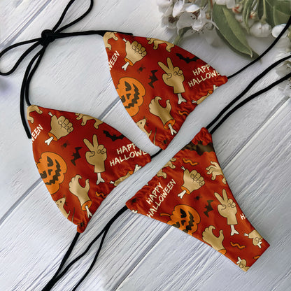 Red orange skull print bikini set on white wood background with Halloween pumpkin and hand graphics triangle top and string ties