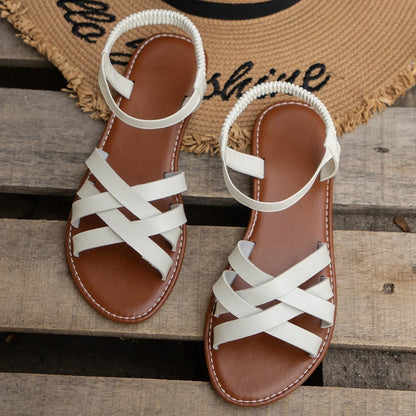 EtherealBe white strappy summer flat sandals for women with elastic ankle strap and brown cushioned footbed on wooden deck