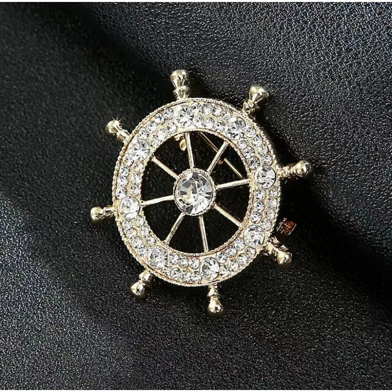 Nautical style crystal brooch in gold featuring a ship's wheel design embellished with sparkling crystals