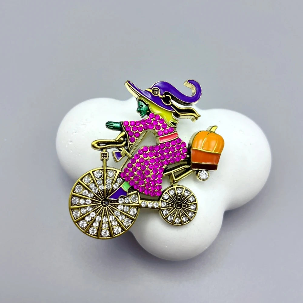 EtherealBe Halloween brooch pins featuring a whimsical witch riding a bicycle with a pumpkin