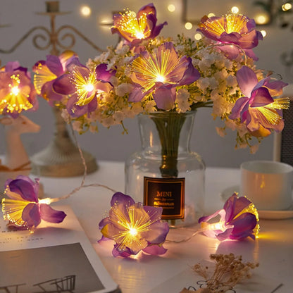 EtherealBe fairy flower string lights with purple flowers illuminating a cozy indoor setting