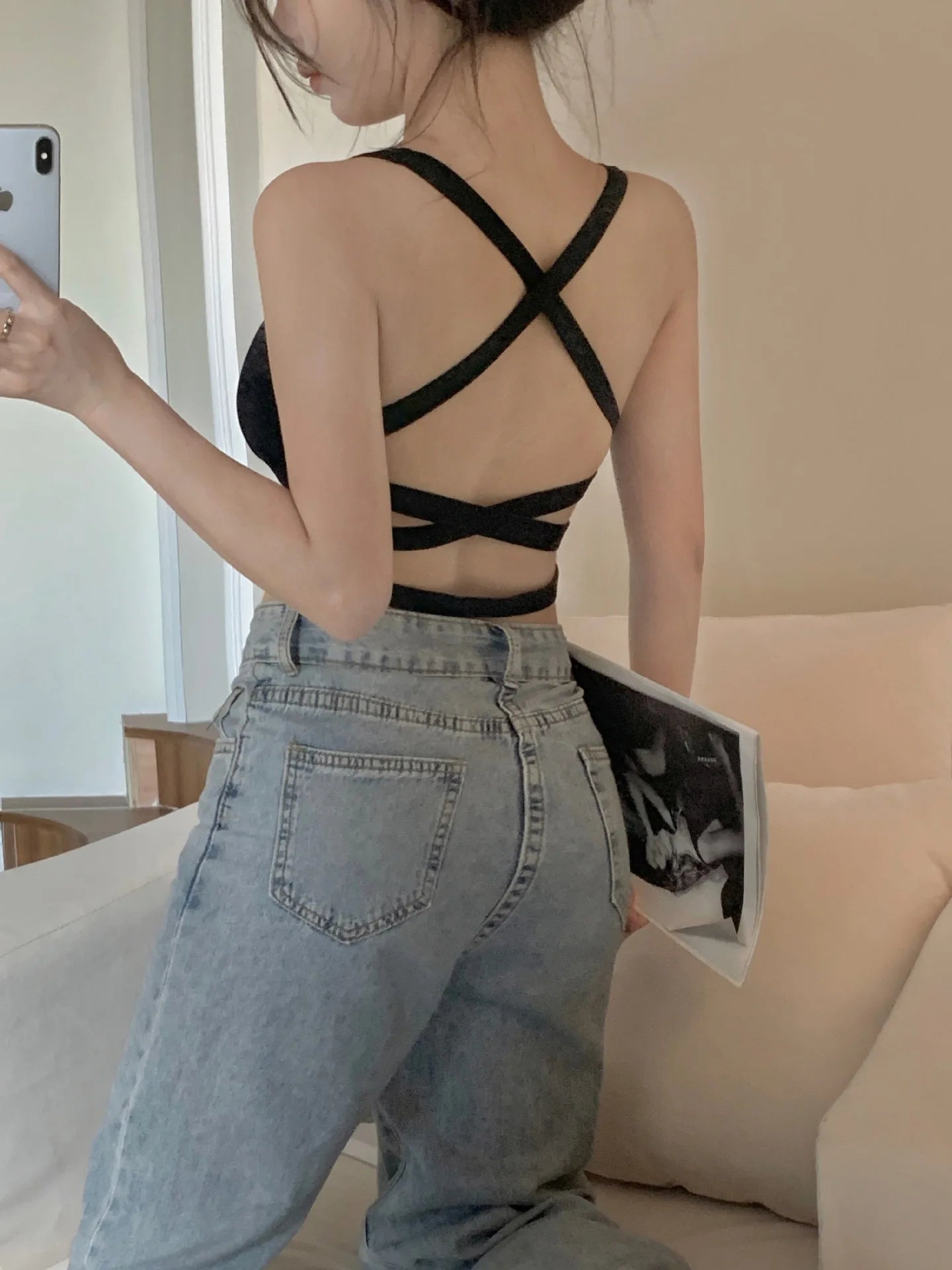 Woman wearing EtherealBe black crisscross back push up sports bra sportswear paired with high waisted jeans