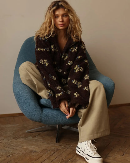 Chic model sitting in a blue chair wearing a cozy lambskin coat for women with floral patterns