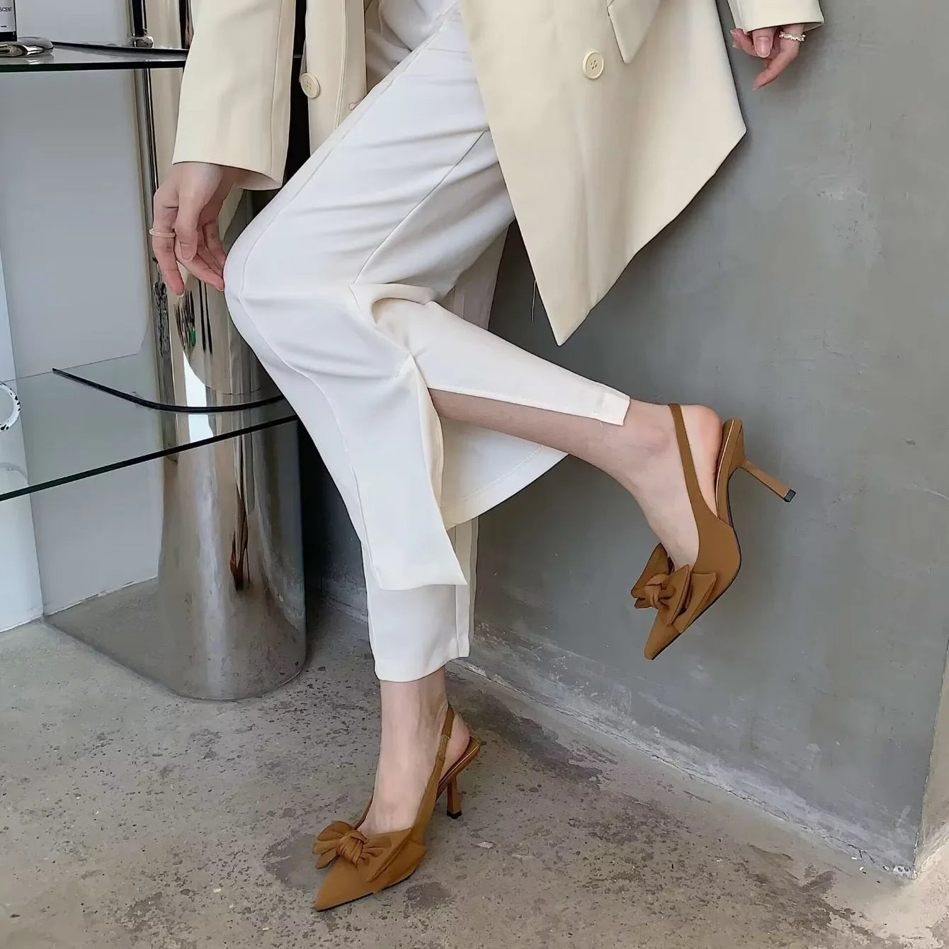 Brown women's butterfly high heel sandals with bow detail, styled with tailored white pants