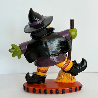Colorful Halloween witch figurine with a broomstick and playful pose, perfect for holiday decor
