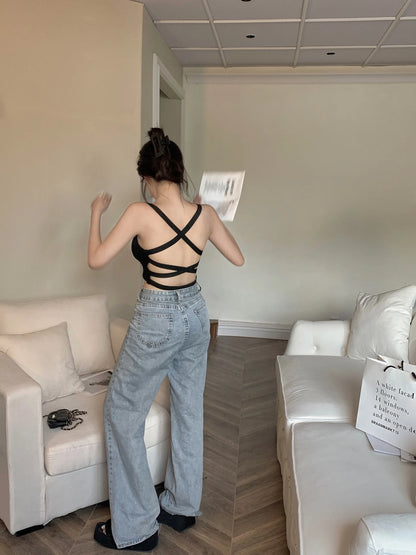 Back view of woman wearing EtherealBe black crisscross push up sports bra sportswear with high waist wide leg jeans in living room
