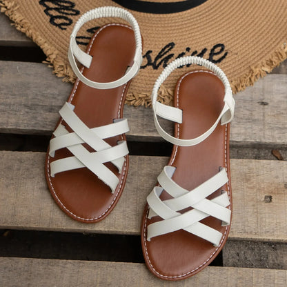White crisscross leather summer flat sandals for women with brown cushioned footbed and elastic ankle strap