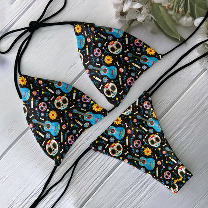 EtherealBe skull print bikini set with black ties and colorful sugar skulls guitars and flowers laid flat