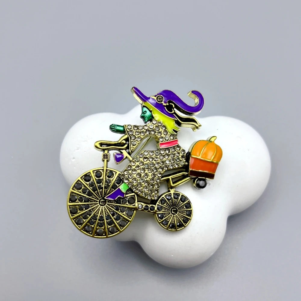 EtherealBe Halloween brooch pins featuring a whimsical witch on a bicycle with sparkling details
