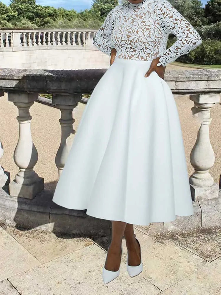 Model wearing elegant lace party dress for women with long lace sleeves high neckline and full white midi skirt