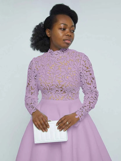 Woman in lilac elegant lace party dress for women with high neck long sleeves holding white clutch