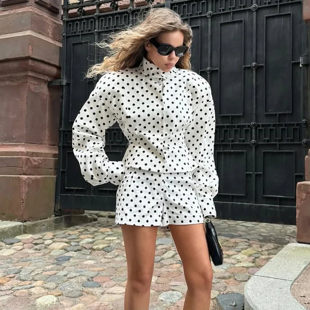 Woman wearing white casual chic polka dot matching set with long sleeve jacket shorts and sunglasses