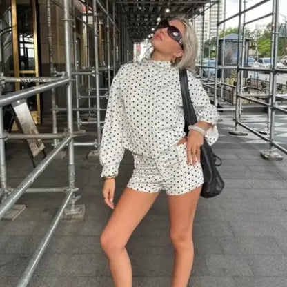 Model wearing casual chic polka dot matching set white long sleeve top and shorts with sunglasses bag