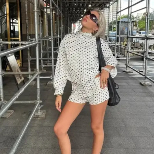 Model wearing casual chic polka dot matching set white long sleeve top and shorts with sunglasses bag