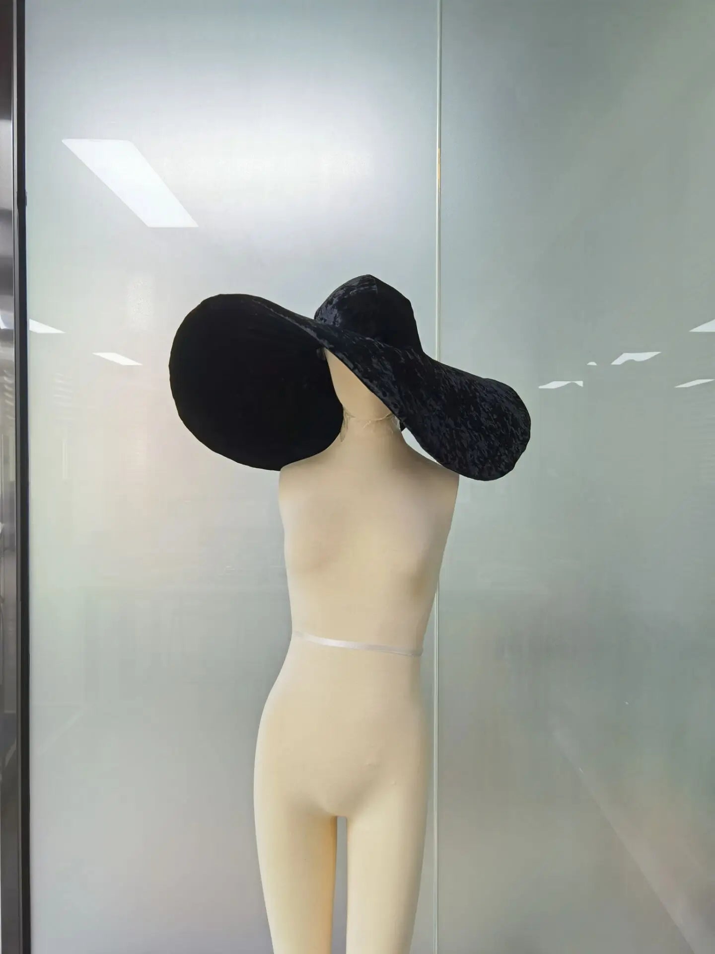 Elegant black velvet large brim hat displayed on a mannequin for stylish outdoor fashion