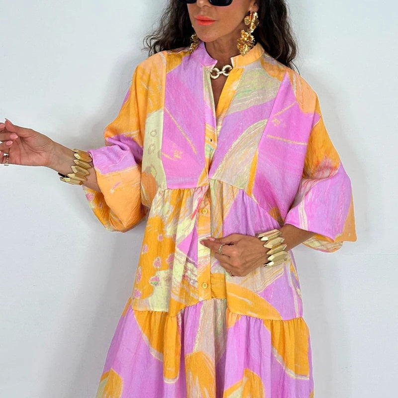 Model wearing an elegant printed v-neck maxi dress in pink and yellow abstract print with buttons