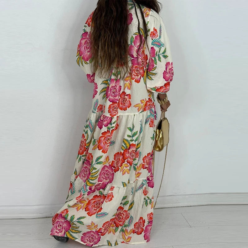 Back view of woman wearing an elegant printed v-neck maxi dress cream with bold pink orange floral tiers and puff sleeves