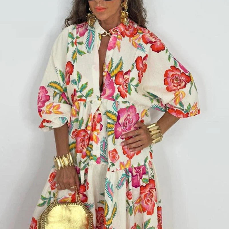 Woman wearing an elegant printed v-neck maxi dress with bold floral print tiered skirt gold round bag and statement bracelets