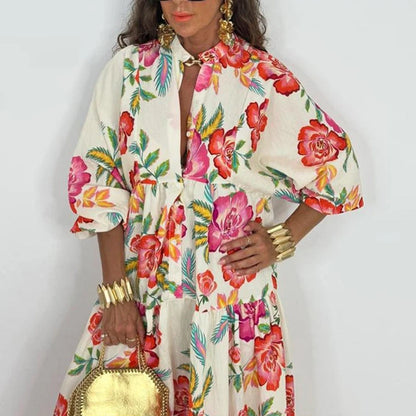 Woman wearing an elegant printed v-neck maxi dress with bold floral print tiered skirt gold round bag and statement bracelets