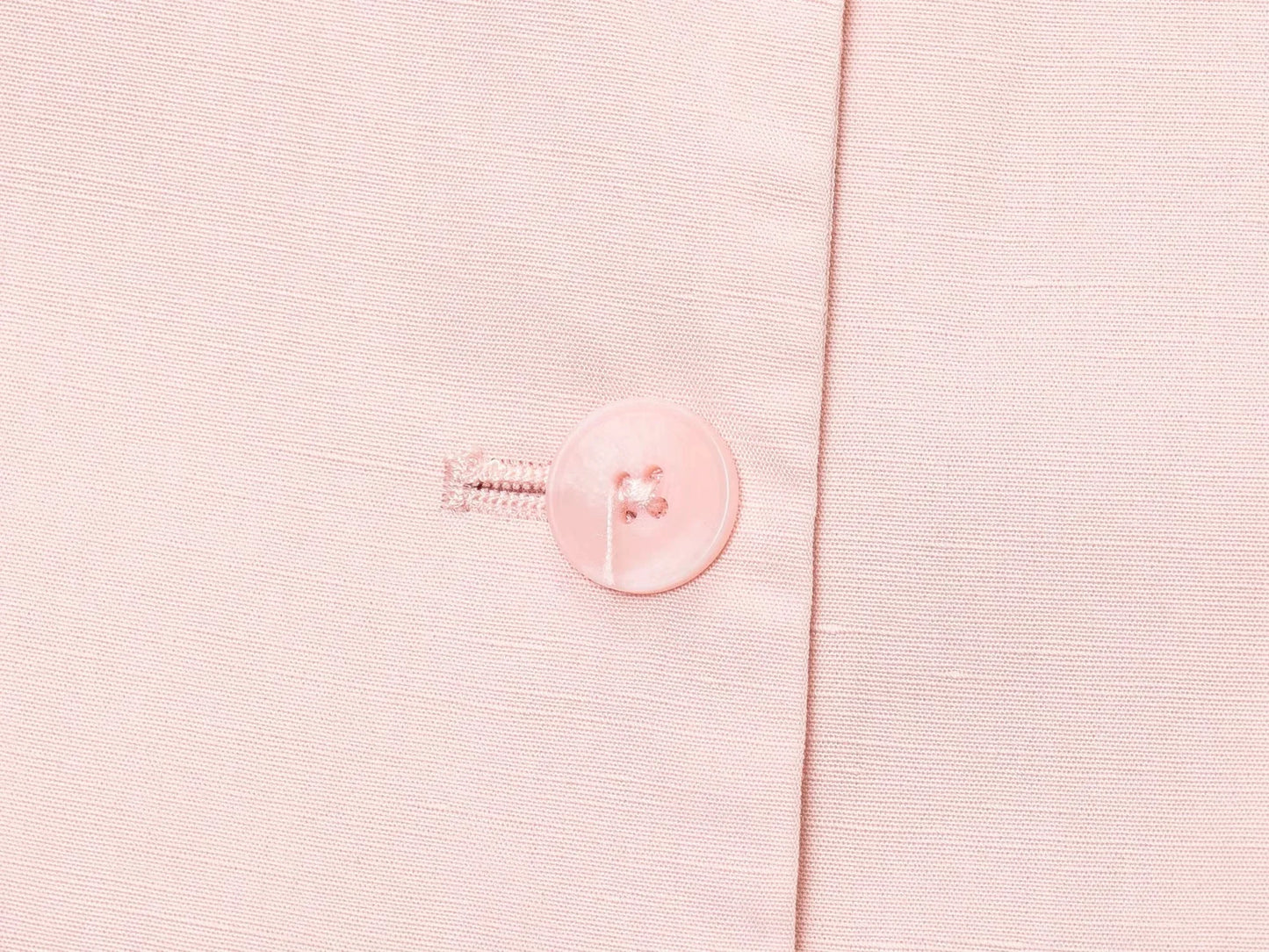 Close-up of pink button detail on casual chic office lady pantsuit fabric