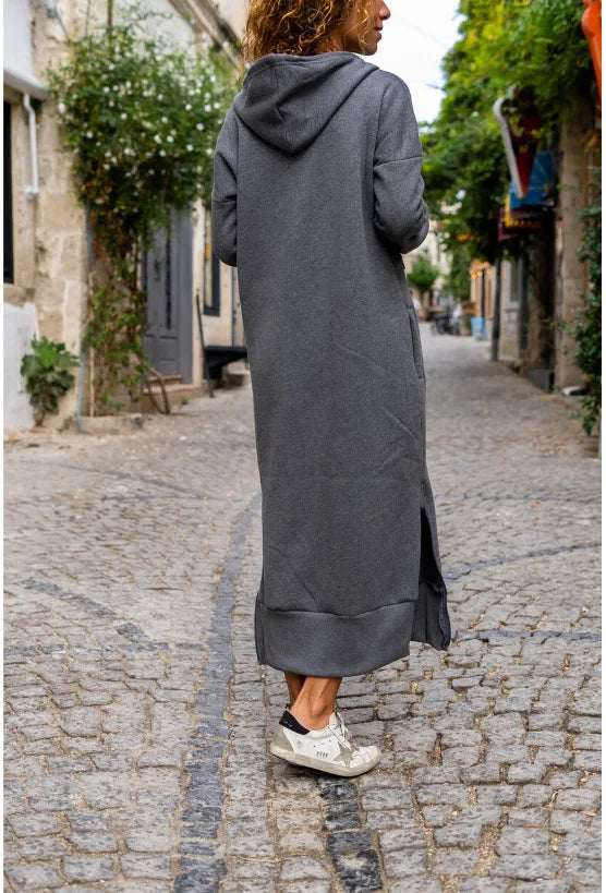Model wearing a casual hooded V-neck dress in gray, walking on a cobblestone street