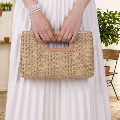 Chic straw woven shoulder bag held by a person in a white dress with a stylish design