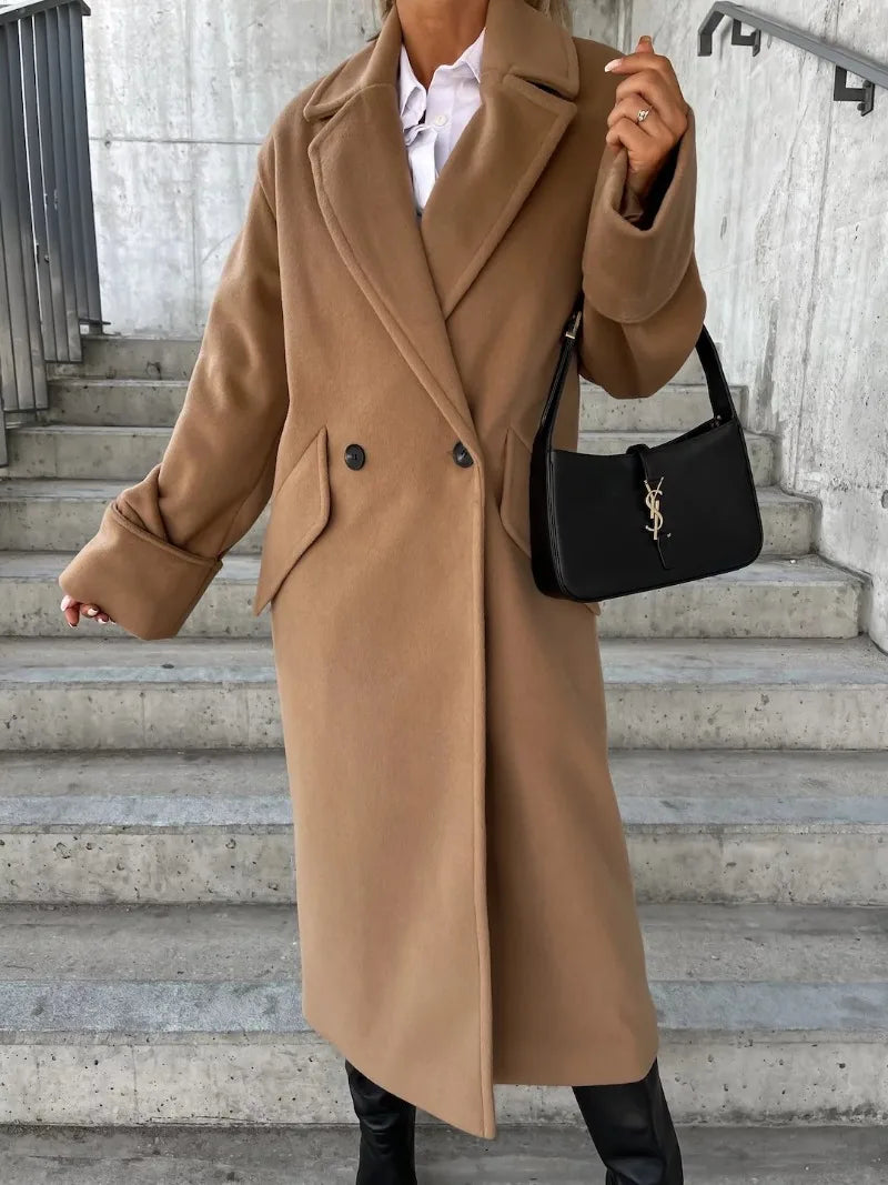 Camel double breasted elegant long coat for women with wide lapels cuffed sleeves side pockets styled with black bag