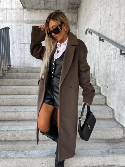 Model wearing elegant long coat for women in dark brown over white blouse and black leather shorts