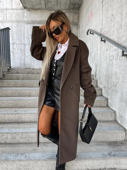 Model wearing EtherealBe elegant long coat for women in chocolate brown over leather romper and knee high boots