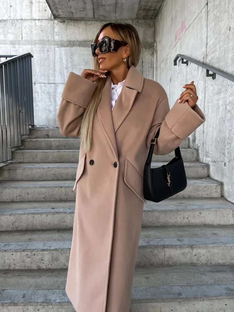 Woman wearing an elegant long coat for women in camel double breasted wool style with oversized cuffs and black handbag