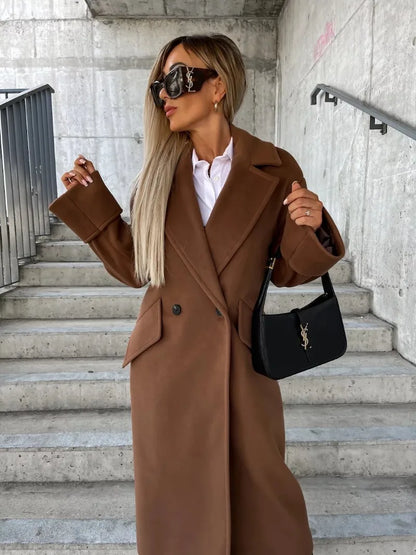 Woman wearing brown double breasted elegant long coat for women with white shirt sunglasses and black bag on concrete steps