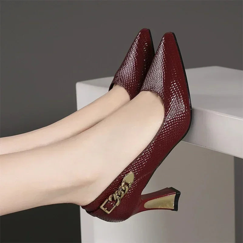Elegant designer party pumps in deep red patent leather with stylish pointed toes and gold accent