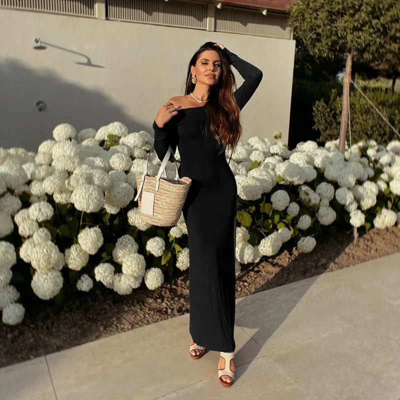 Stylish woman in an elegant off shoulder evening dress posing outdoors with flowers