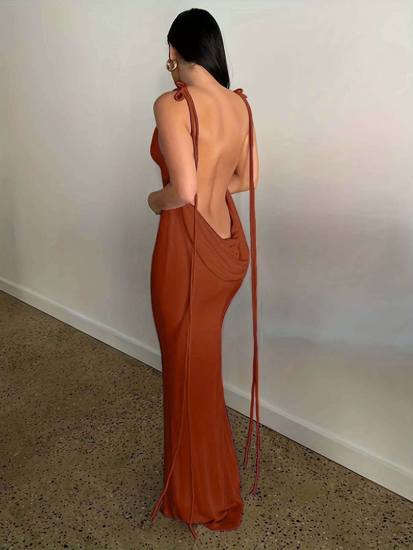 Back view of an elegant womens strapless evening gown in rust color with flowing draped fabric