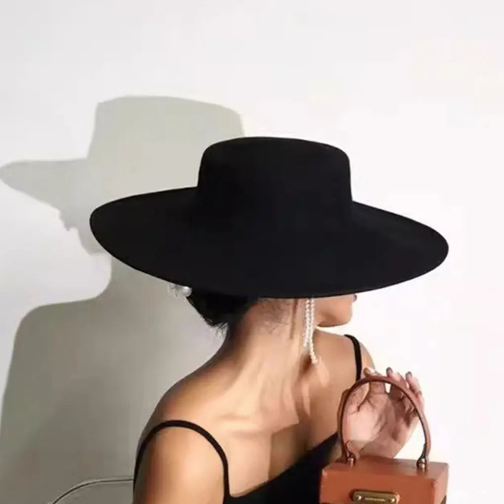 Elegant black fashion blend top hat for ladies with wide brim, stylishly paired with a handbag