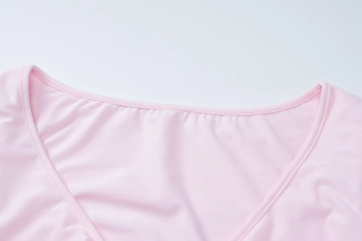 Close-up of the neckline detailing on a flared sleeved v neck ruffle dress in soft pink fabric