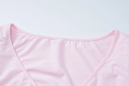 Close-up of the neckline detailing on a flared sleeved v neck ruffle dress in soft pink fabric