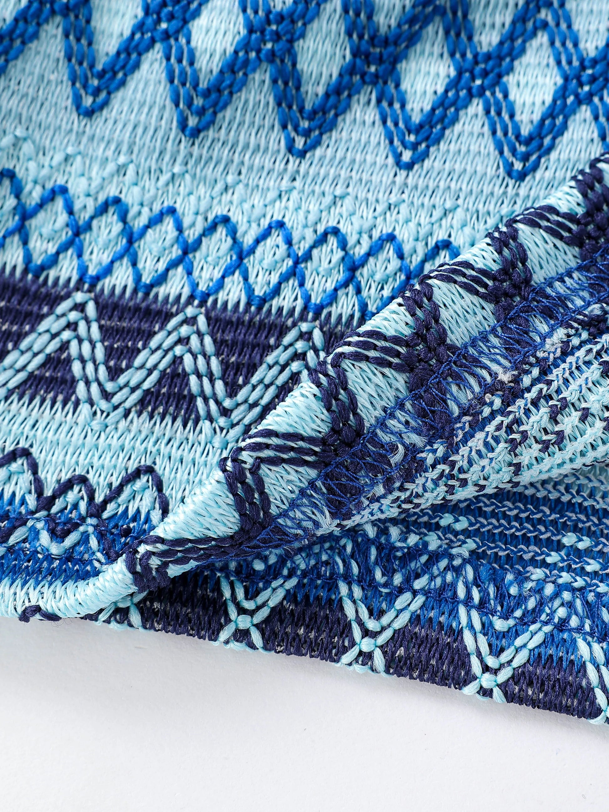 Close-up of geo pattern beaded halter crop top featuring intricate blue and navy stitching