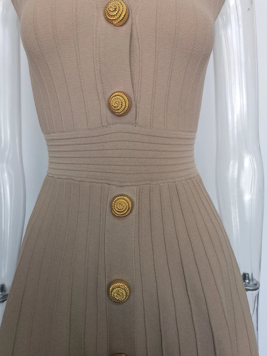 Close-up of a beige V-neck sleeveless fall dress for women featuring decorative buttons and ribbed texture