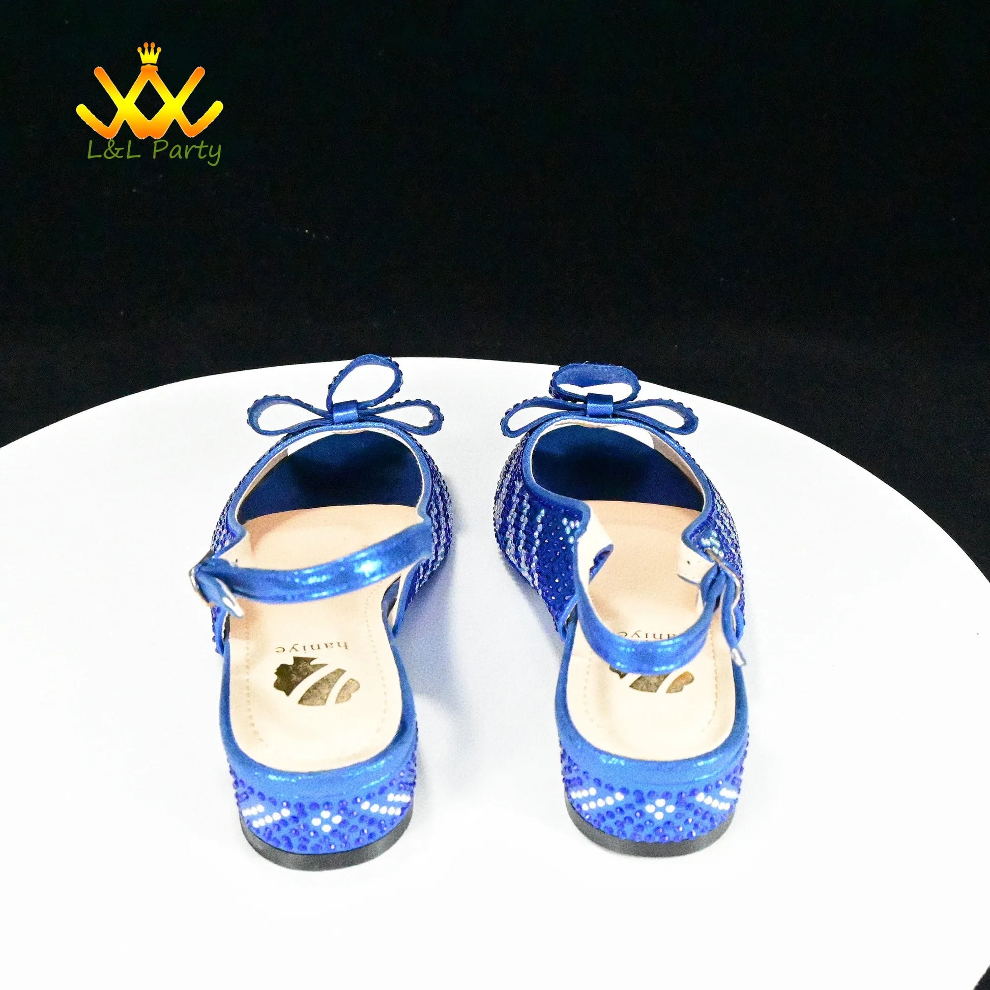 Blue sequined girls sandals with ankle bow and adjustable strap on white display stand Fashionable shoes and bag set.