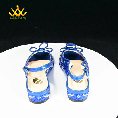 Blue sequined girls sandals with ankle bow and adjustable strap on white display stand Fashionable shoes and bag set.