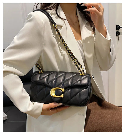Black quilted leather luxury square chain handbag with gold chain strap and C clasp worn by model