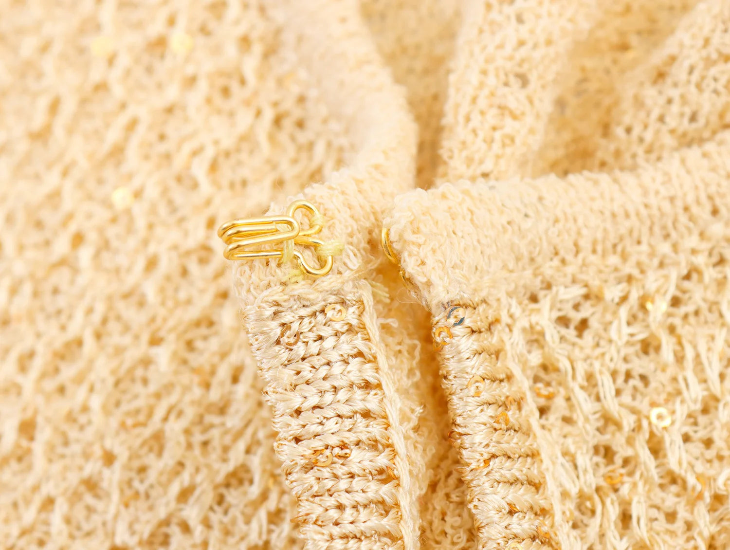 Detailed view of a pearl embellished knitted vest for women featuring a decorative clasp