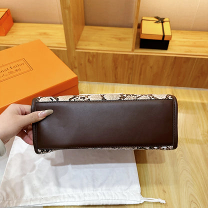 Hand model holding a snake print leather shoulder bag with a brown bottom, showcasing its stylish design