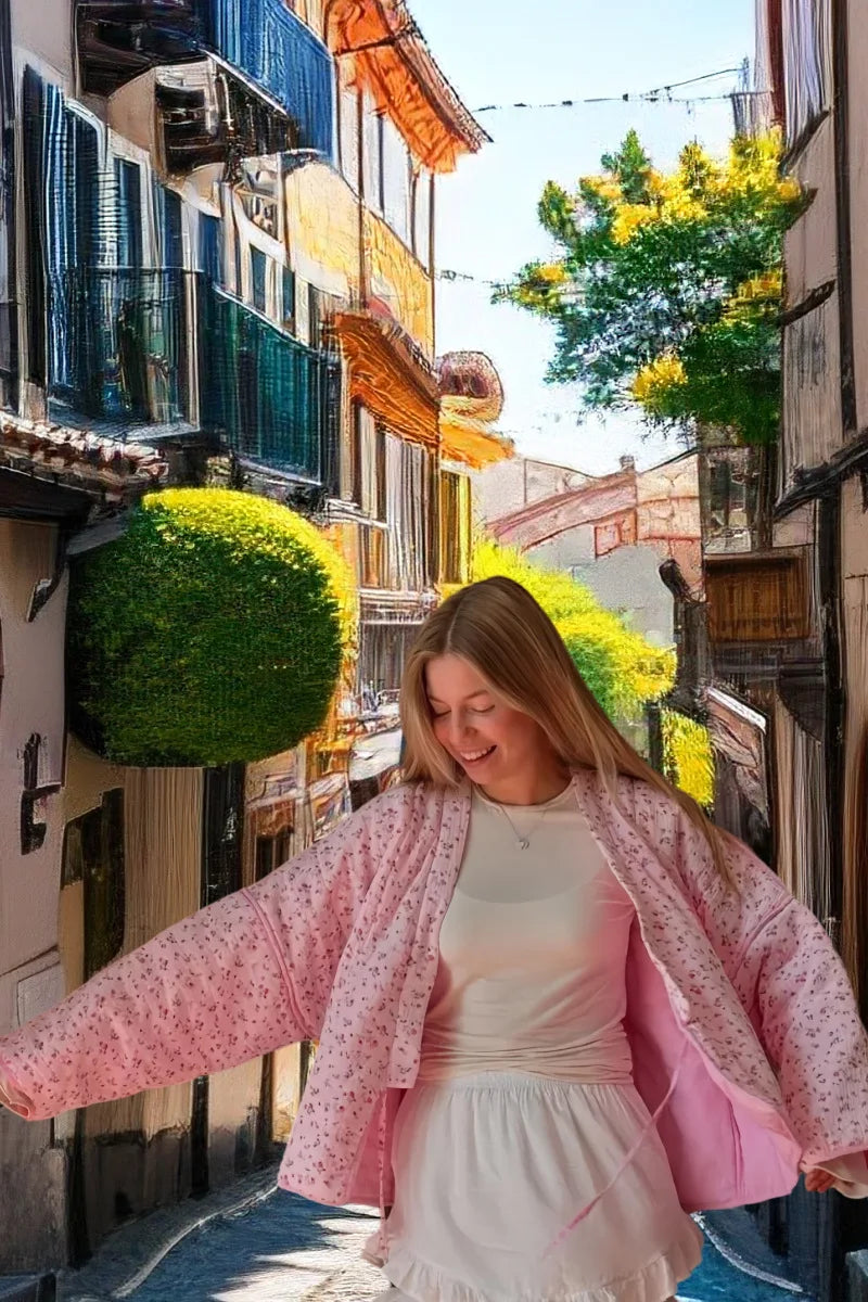 Young woman wearing a pink floral cotton jacket for women, smiling in a picturesque street setting