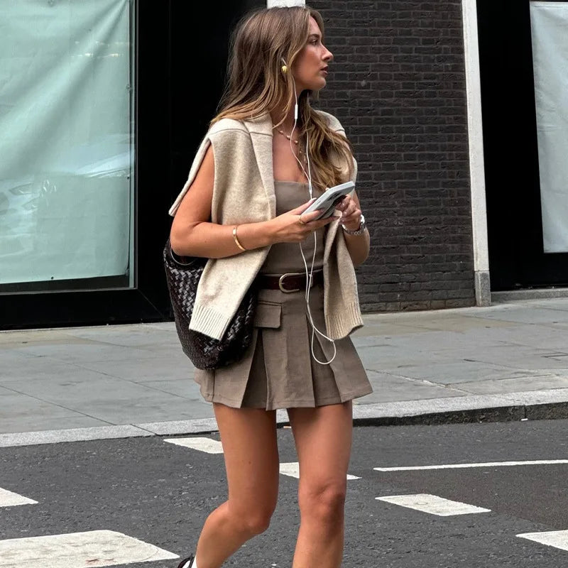 Fashionable model wearing a pleated skirt slim fit dress paired with a stylish vest and accessories