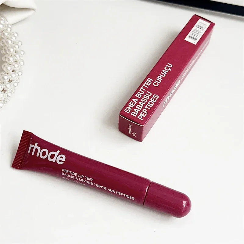 Berry peptide lip tint tube and matching box on white surface with pearls Flavored moisturizing lip balm for dry lips.