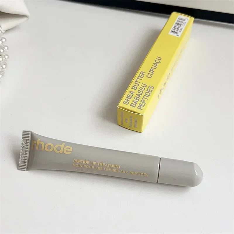Rhode peptide lip treatment tube with yellow box on white surface Flavored moisturizing lip balm for dry lips.
